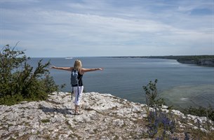 kvinne med utstrakte armer vendt mot havet