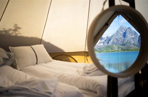 Seng i telt med utsikt over Lofoten. Foto.
