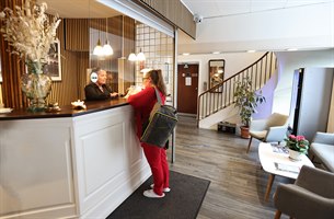 To personer i hotellets resepsjon. Bilde.