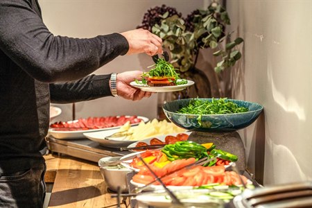 En mann tar mat fra frokostbuffeen. Bilde.