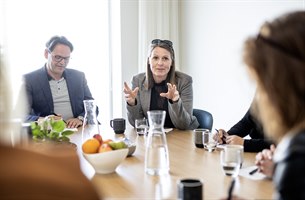 Tre personer ved et konferansebord. Bilde.