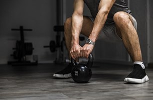 En mann holder en kettlebell. Bilde.