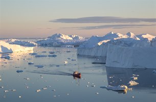 En rød fiskebåt på Ilulissat Isfjord. Bilde.